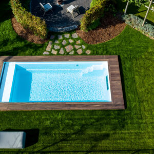 Volledig ingegraven houten zwembad met houten boord, strak geïntegreerd in een ruime tuin