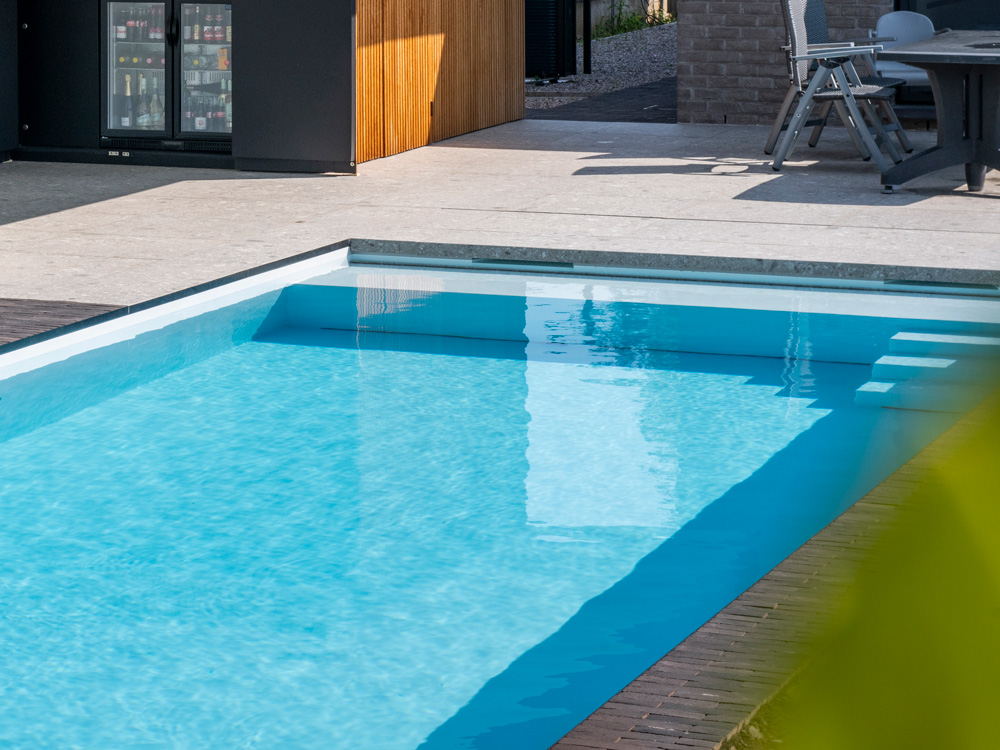 Close-up van een strak PPC zwembad met ingebouwde trap en heldere waterlijn