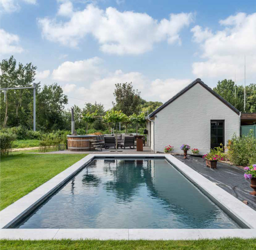 Polypropyleen zwembad met lichte boordstenen in een ruime tuin naast een woning