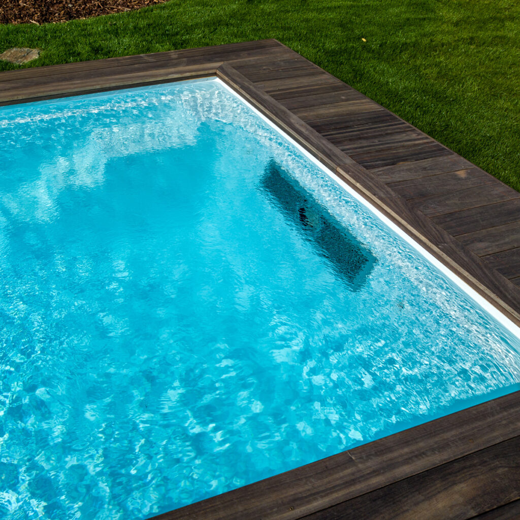 Detail van een vinylester zwembad met gladde wanden en strak houten boord