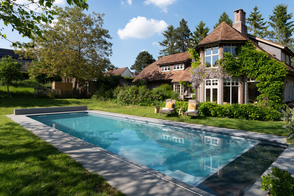 Niet-overdekt zwembad in een ruime achtertuin bij een woning, voorbeeld van een zwembad dat in België vaak zonder bouwvergunning mogelijk is
