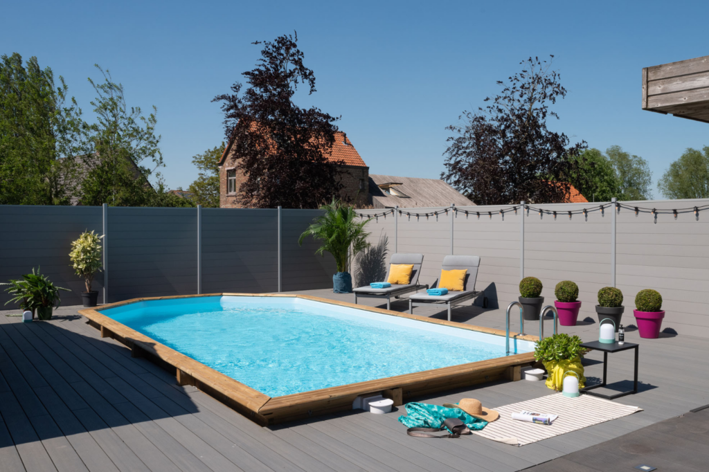 Houten zwembad in een strakke tuinsetting met terras en loungestoelen.