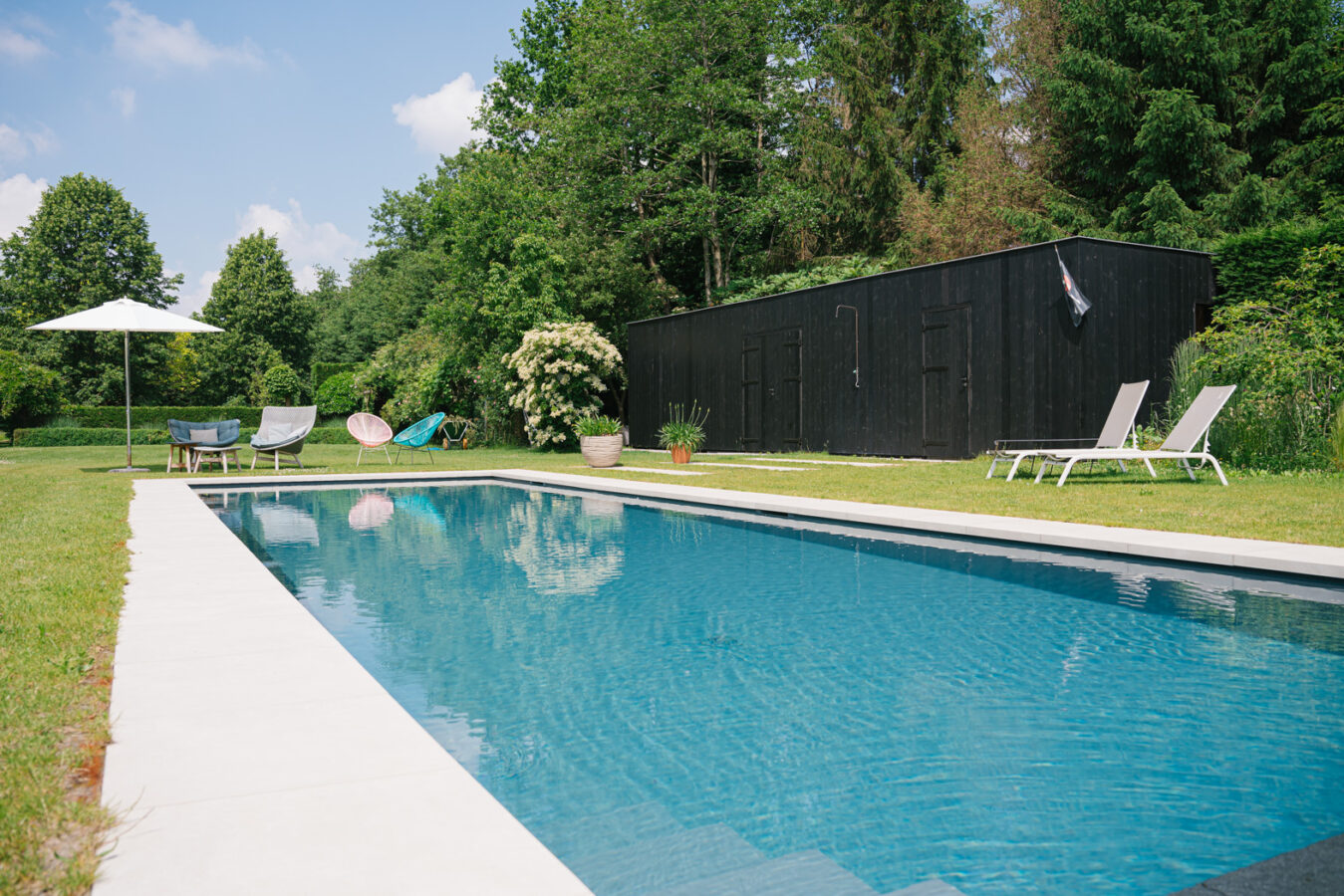 Strak ingebouwd zwembad in een groene tuin, een voorbeeld van een duurzame zwembadoplossing met hogere aanlegkost