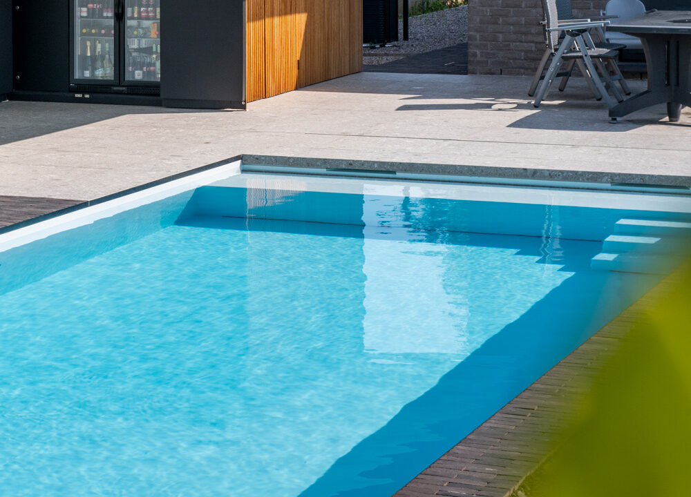 Strak monoblok zwembad met naadloze kuip en ingebouwde trap, omringd door een modern terras