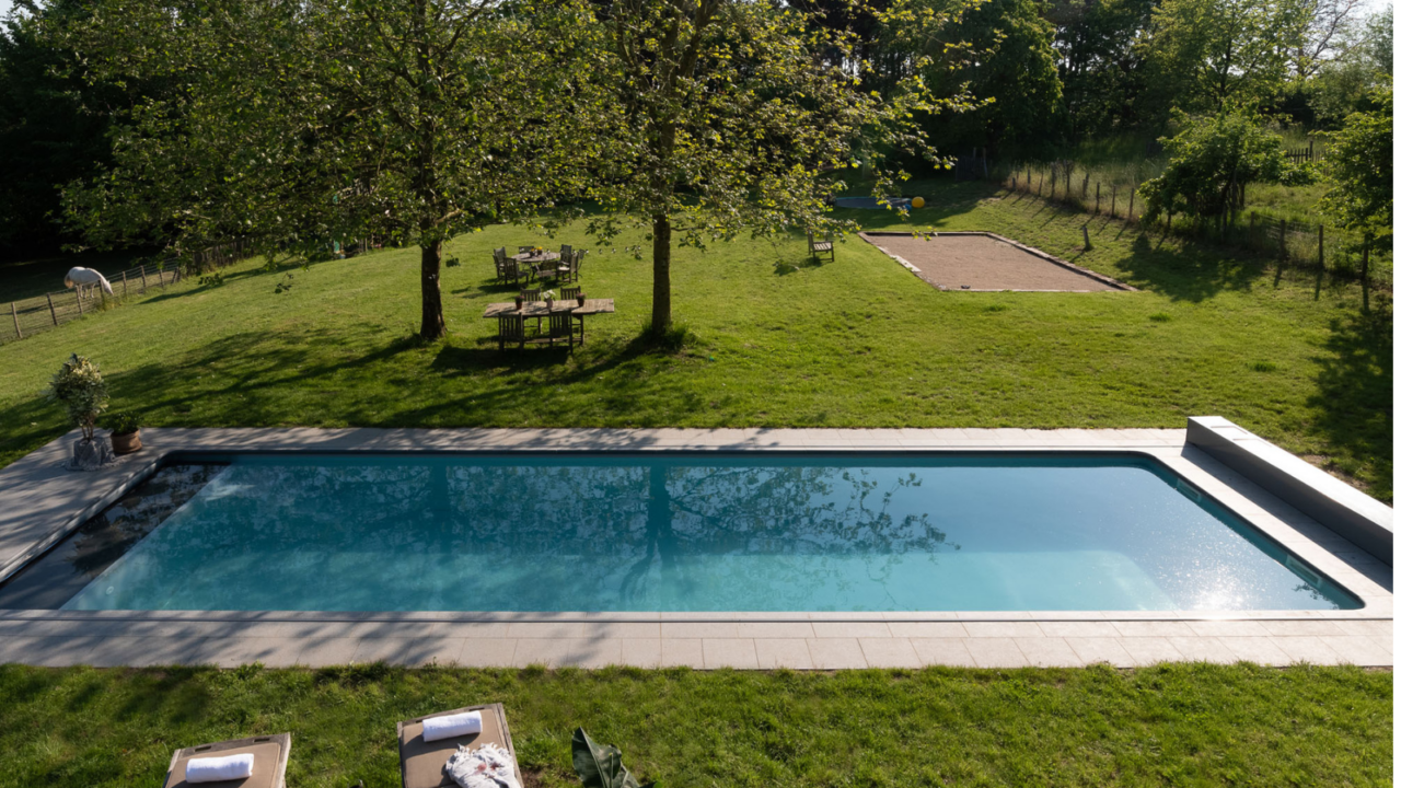 Modulair zwembad in een ruime tuin met zicht op groen en speelse indeling.