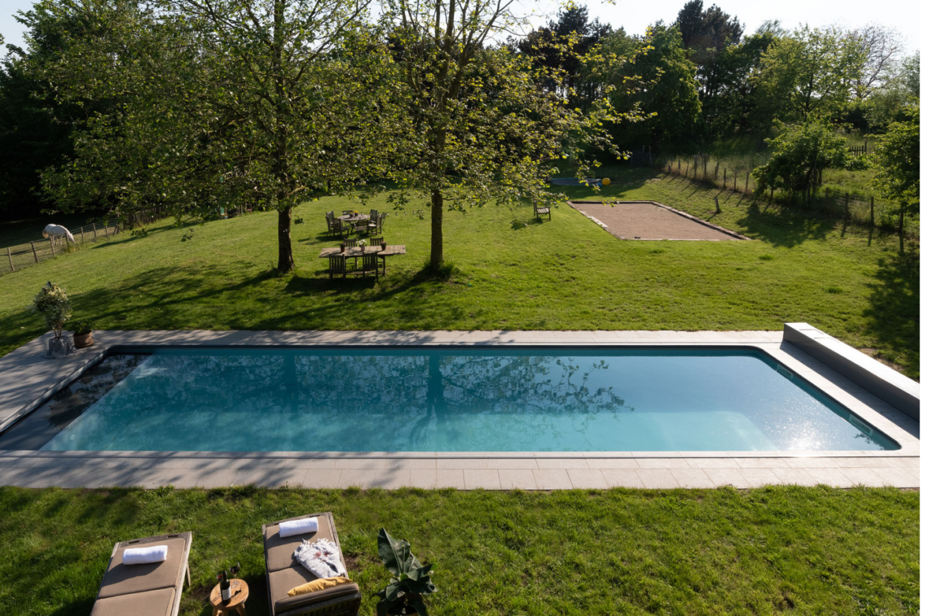 Modulair zwembad in een ruime tuin met zicht op groen en speelse indeling.