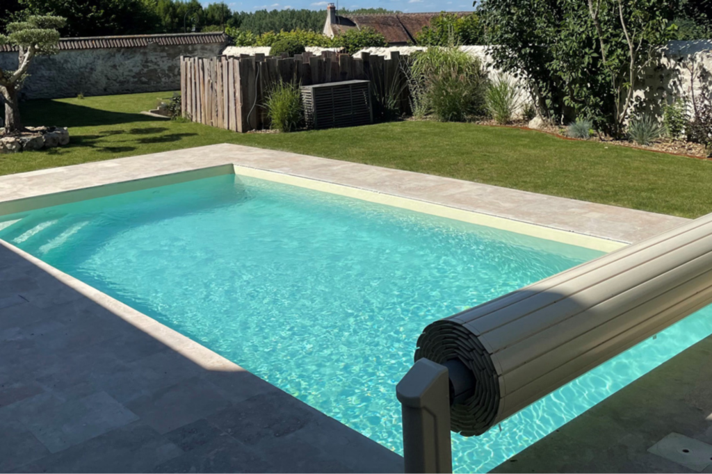 Strak ingegraven modulair zwembad van Infiniteau met rolluikafdekking, mooi geïntegreerd in een groene tuin
