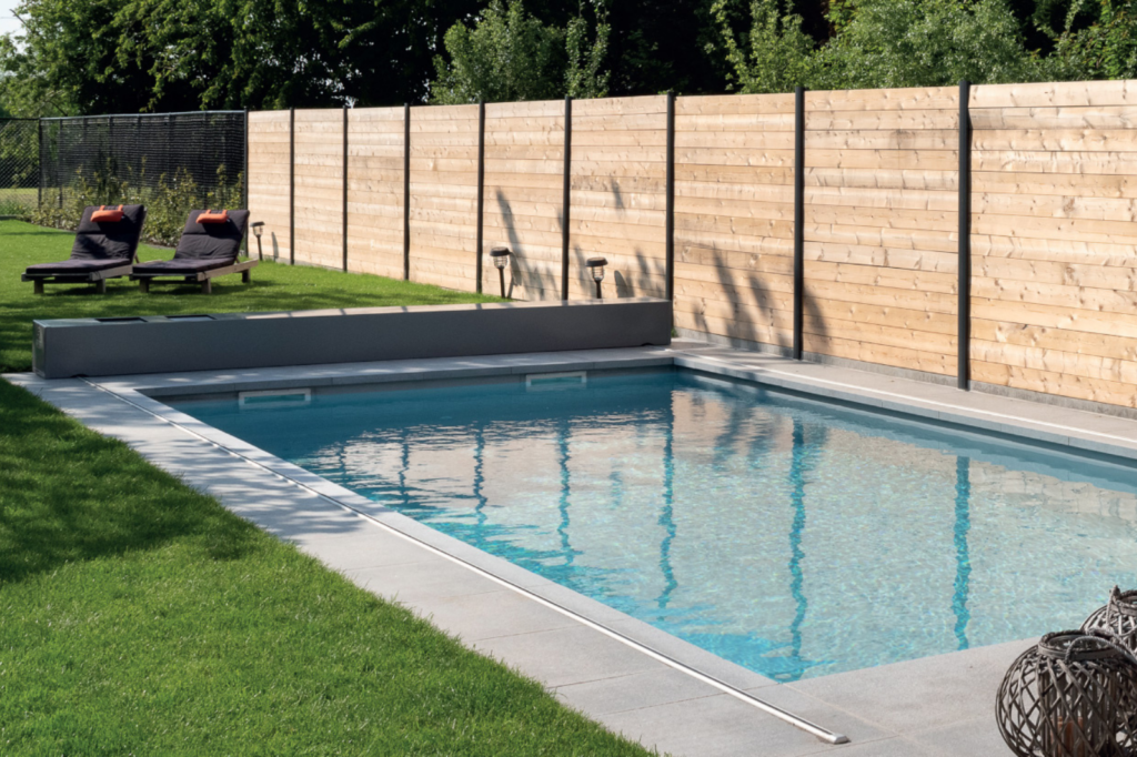 Modern monoblok zwembad met strakke afwerking en ligstoelen in de tuin.