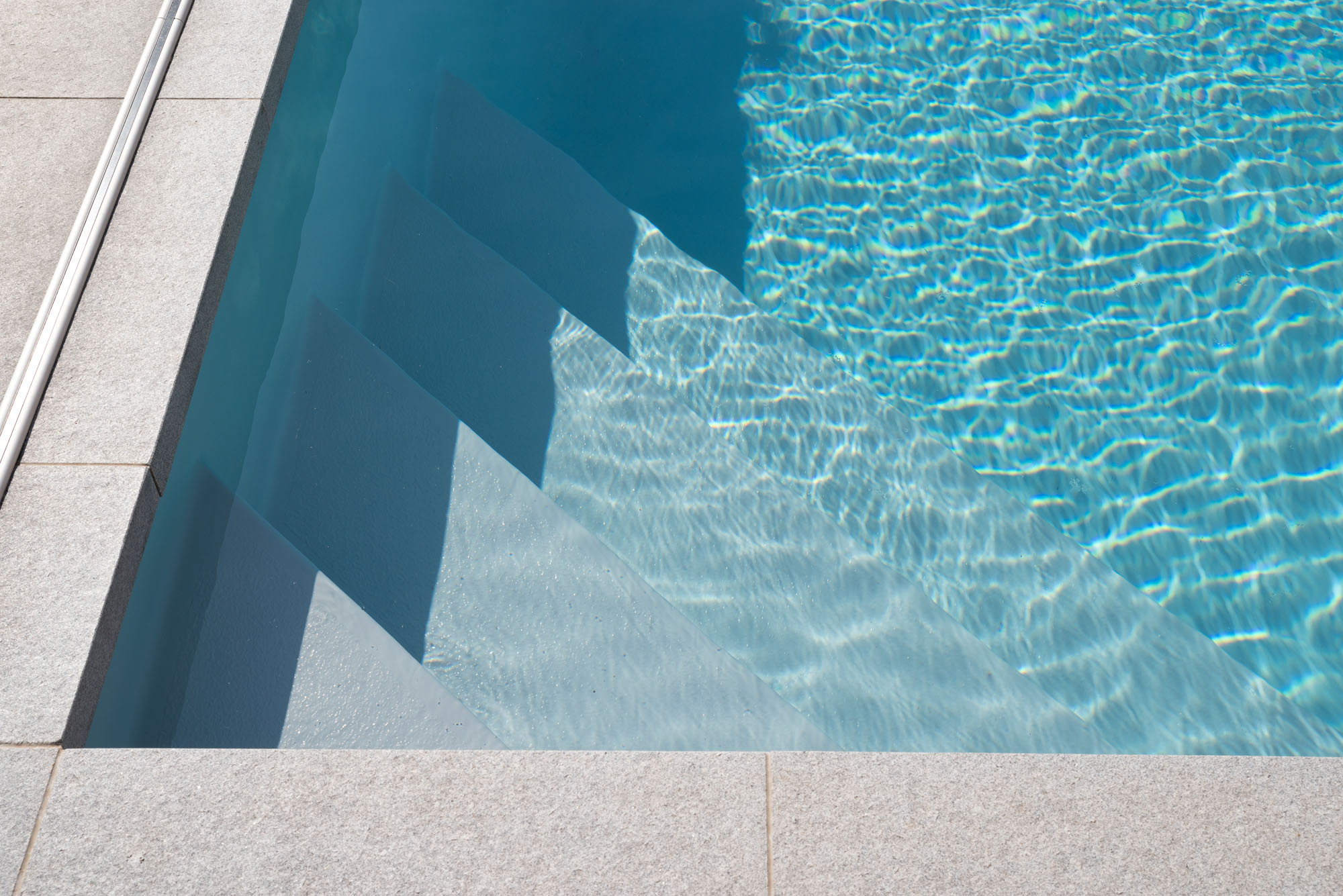 Kristalhelder zwemwater met ingebouwde traptreden in een monoblok zwembad van Alegria Pools.