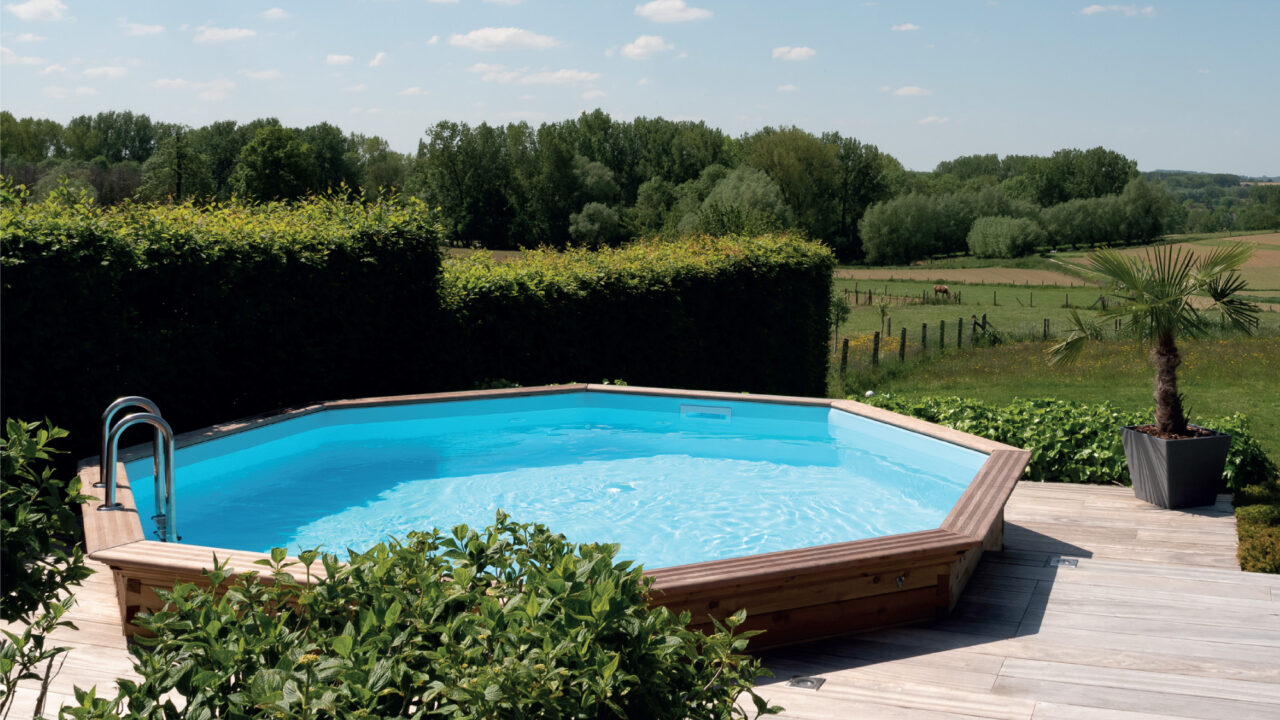 Houten zwembad met ladder en helder blauw water in een landelijke tuin, mooi onderhouden
