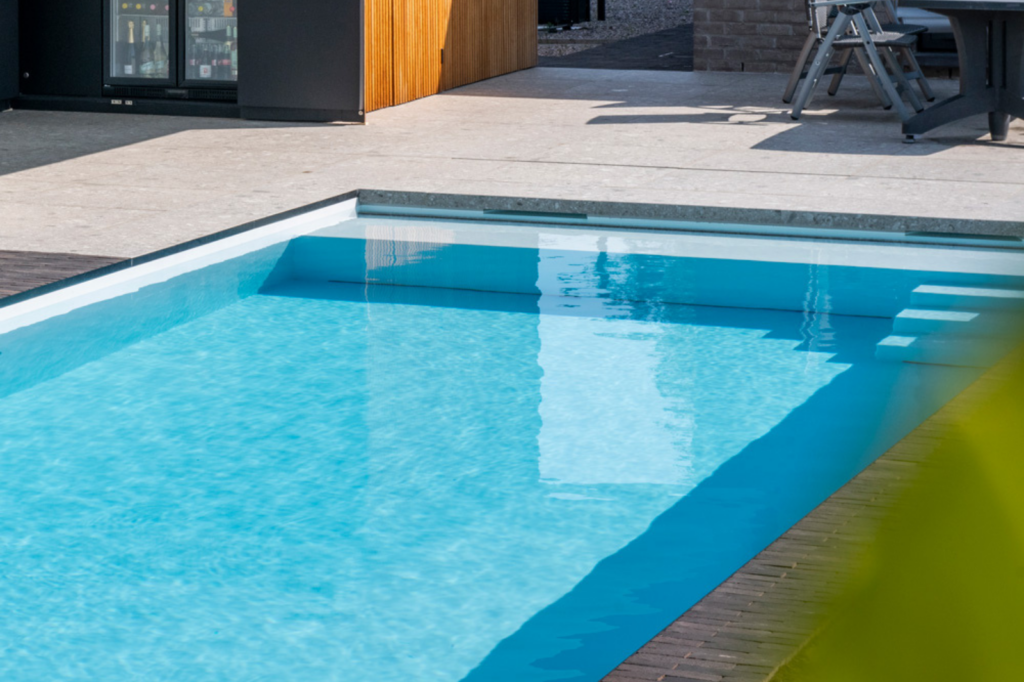 zwembad-detail-heldere-waterbalans Close-up van een zwembadrand met heldere waterspiegel bij een moderne poolhouse.